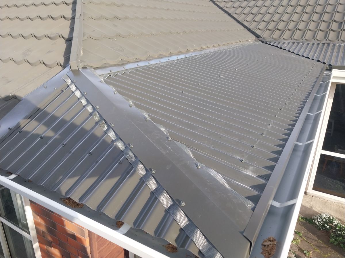 New long-run steel roof section with an external gutter replacing a concealed one
