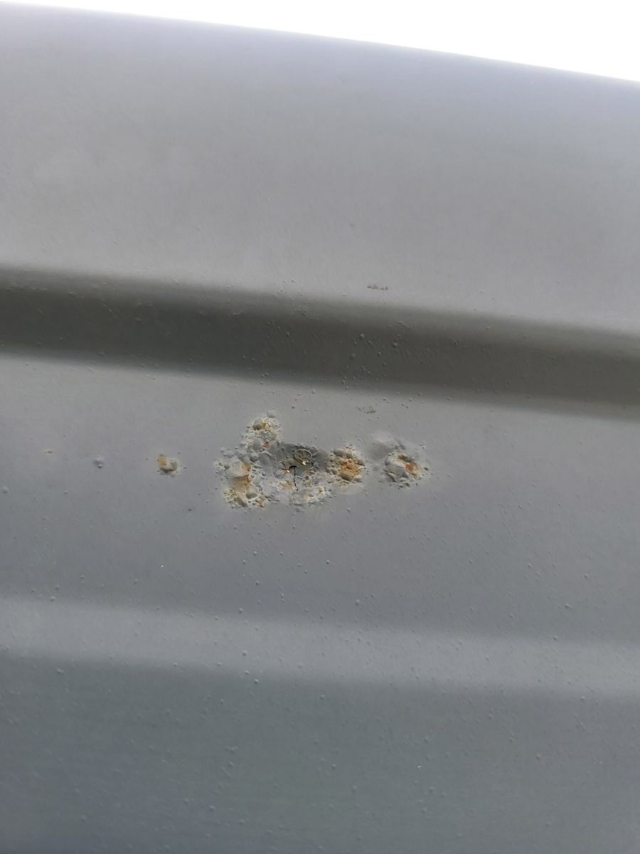 Brown rust spot bleeding through a painted metal fascia
