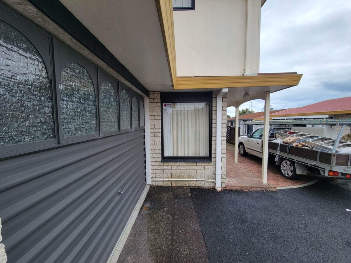 Sagging soffit lining above a corner window on a plastered home