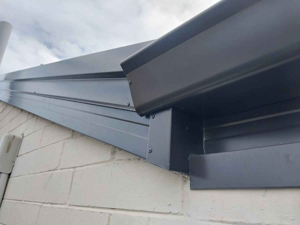 New charcoal external fascia and gutter detail against a painted block wall
