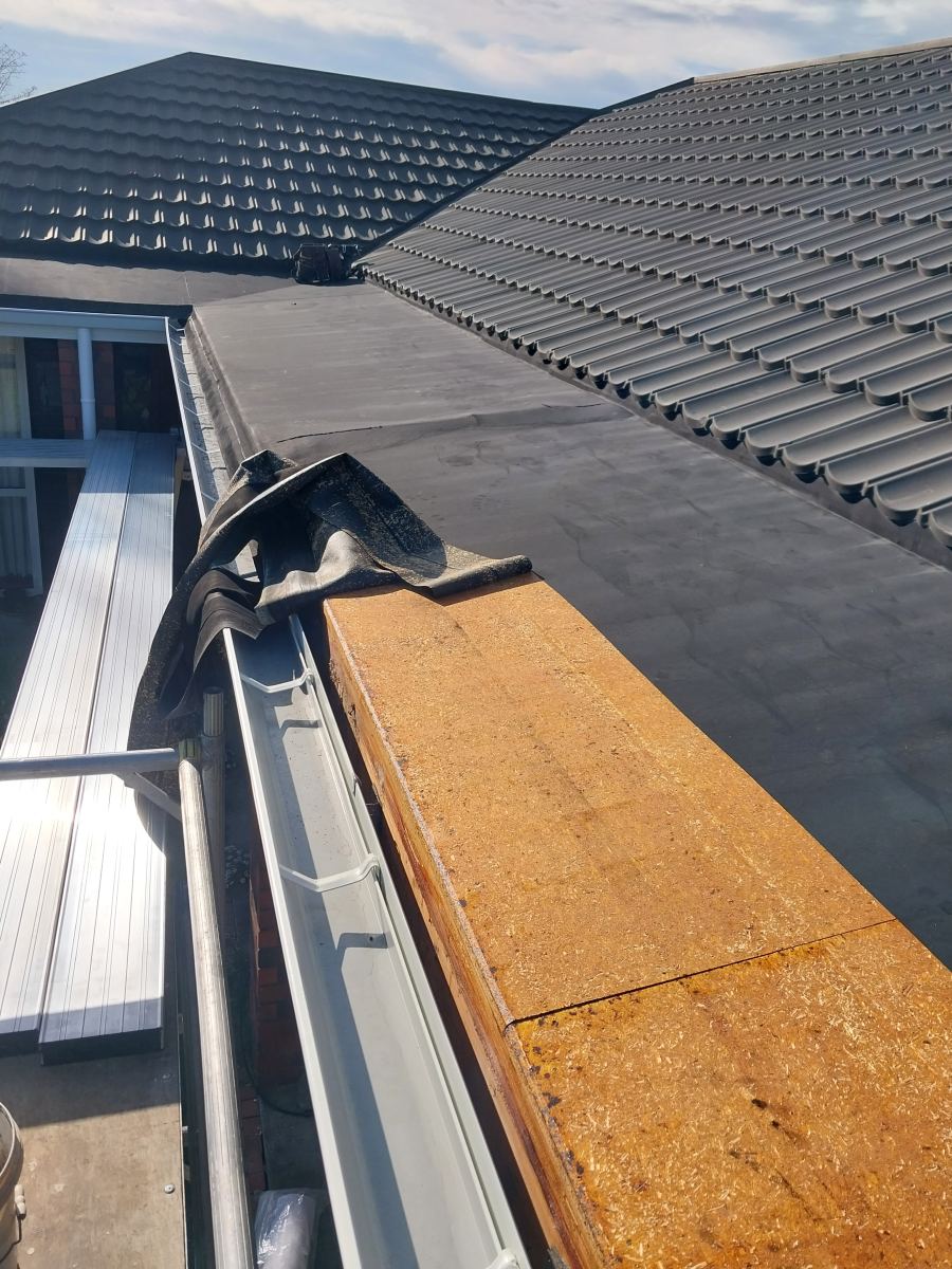 Failed gutter corner with the old membrane peeled back off sodden decking