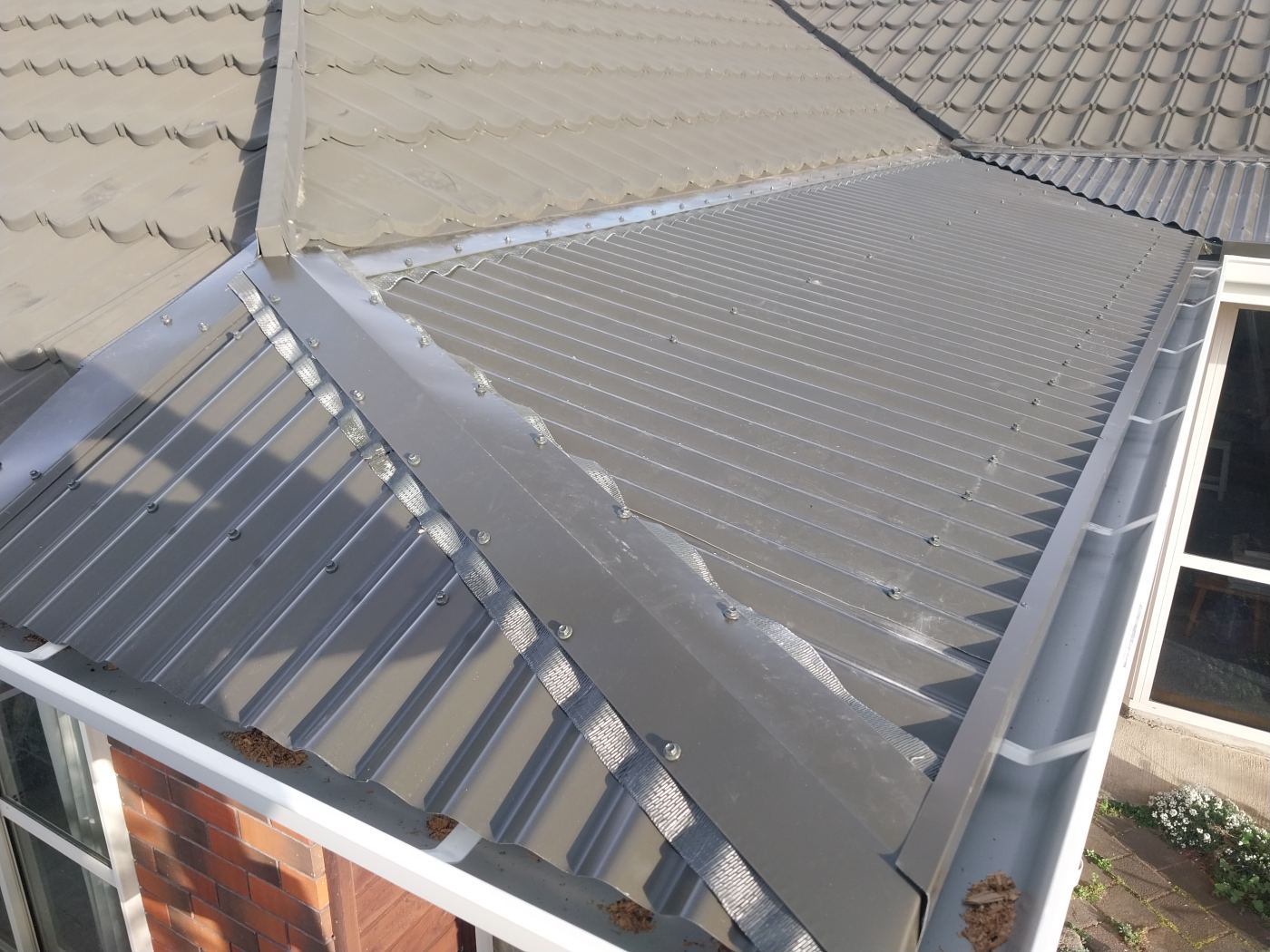 New long-run steel roof section with a new external gutter installed