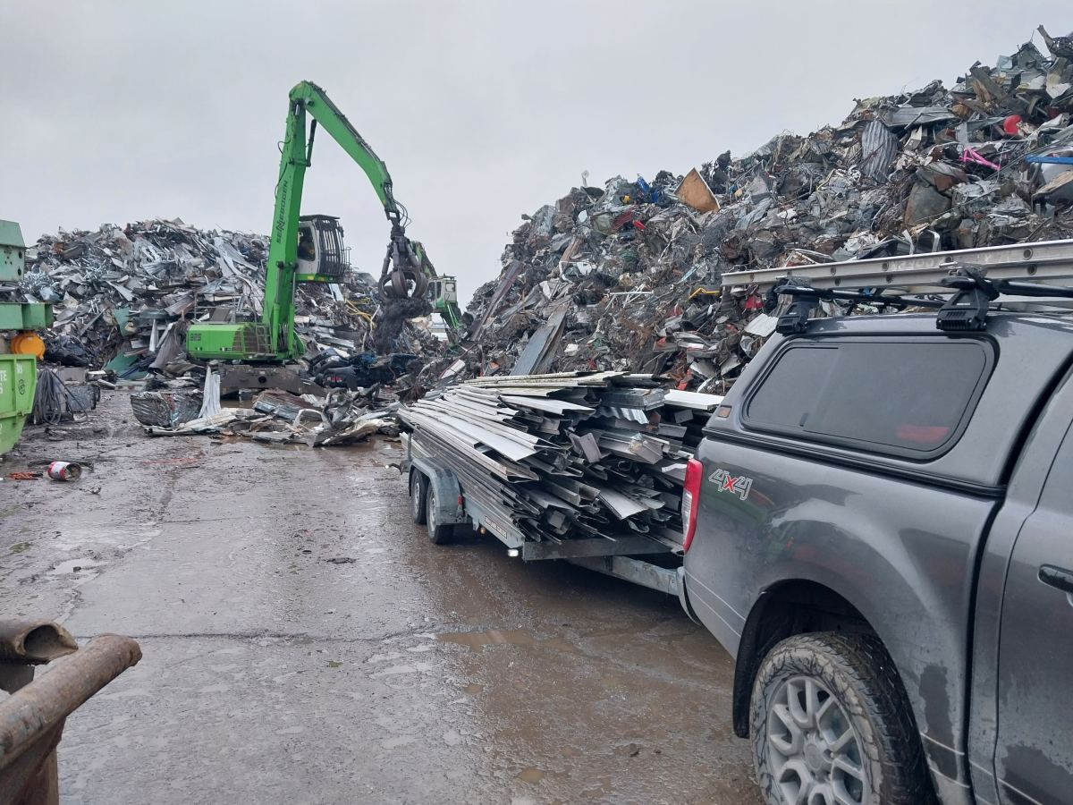 Ute and trailer of old roofing steel unloading at a scrap metal recycling yard
